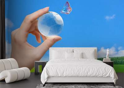 Glass globe of the planet Earth in human hand and flying butterfly Wall mural