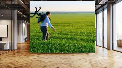 businessman carries an office chair in a field to work, freelance and business concept, green grass and blue sky as background Wall mural