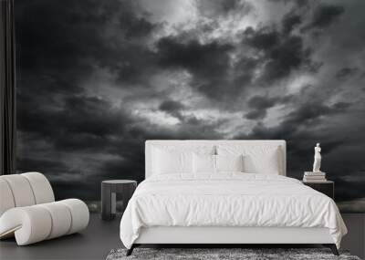 dark dramatic sky with black stormy clouds before rain or snow as abstract background, extreme weather, the sun shines through the clouds, high contrast photo Wall mural