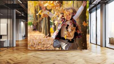 Happy family is in autumn city park. Children and parents running with leaves.. They posing, smiling, playing and having fun. Bright yellow trees. Wall mural