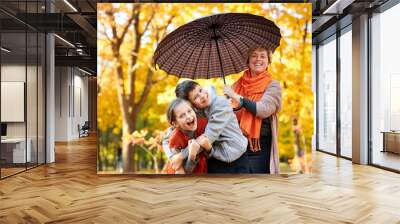 Happy family is in autumn city park. Peoples are posing under umbrella. Children and parents are smiling, playing and having fun. Bright yellow trees. Wall mural