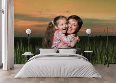 happy mother and child in green field at sunset Wall mural