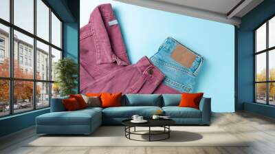 Pink denim jeans jacket with blue jeans, on blue background. Fashion concept. Flat lay, top view Wall mural