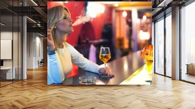 Lonely woman drinking and smoking cigarettes in the bar at night Wall mural