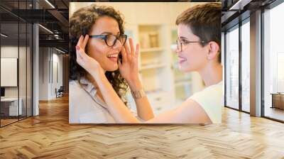 Young beautiful woman choosing eyeglasses in optical shop Wall mural