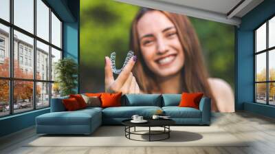 Beautiful smiling Turkish woman is holding an invisalign bracer with vibrant colors Wall mural