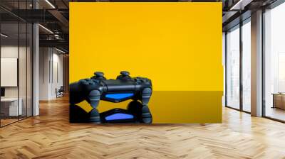 Modern black gamepad on a yellow back. Joystick black color on a smooth reflective table. Gaming concept Wall mural