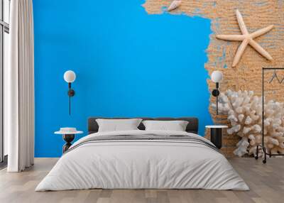 Summer time concept with sea shells and starfish on a blue wooden background and sand. Wall mural