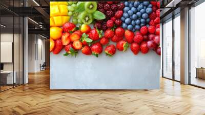 rainbow of fruits: strawberries, blueberries, mango, oranges, grapes, and kiwi on a grey background Wall mural