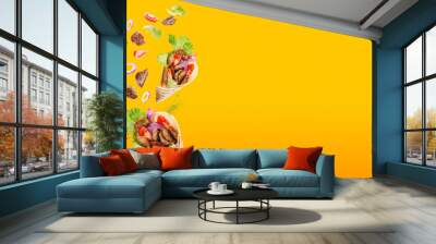 Two doner kebab or shawarma with ingredients floating in the air: beef meat, lettuce, onion, tomatos, spice. Yellow orange background. Copy space. Wall mural