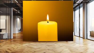 Large lighted candle on a warm yellow background. Wall mural