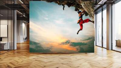 Athletic Woman climbing on overhanging cliff rock with sunset sky background. Wall mural