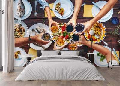 Big family dinner. Vertical top view on served table and hands with clinking goblets Wall mural