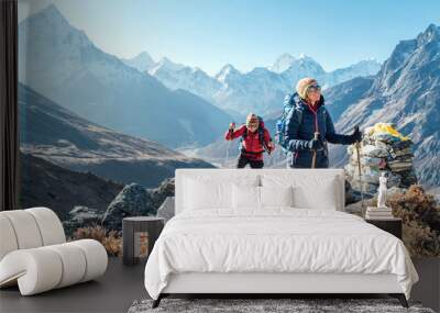 Couple following Everest Base Camp trekking route near Dughla 4620m. Backpackers carrying Backpacks and using trekking poles and enjoying valley view with Ama Dablam 6812m peak Wall mural