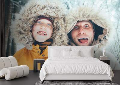 Father and son fooling into the camera. They showing their tongues and making grimaces. Parent and children winter holidays spending concept image. Wall mural