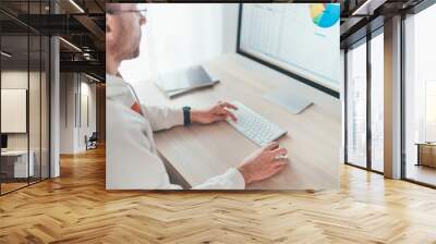 Finance asset manager man in eyeglasses using modern computer with a wireless keyboard and mouse evaluating money growth. Home office, investing or freelance work on worldwide quarantine time concept Wall mural