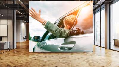 Happy boy looks out from auto window and greets somebody Wall mural