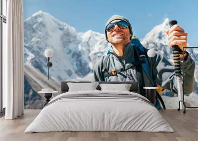 Portrait of smiling Hiker man on Taboche 6495m and Cholatse 6440m peaks background with trekking poles, UV protecting sunglasses. He enjoying mountain views during Everest Base Camp trekking route. Wall mural