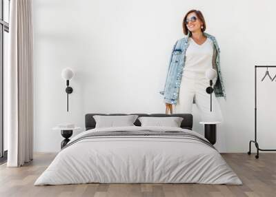 Posing woman in elegant white outfit with oversize denim jacket Wall mural