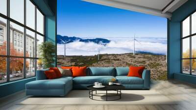 Wind generators with over clouds background and blue sky on clear summer day on the mountain range aerial view, Madeira,Portugal. Green energy concept image. Wall mural