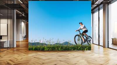 Woman ride a bike: summertime activity Wall mural