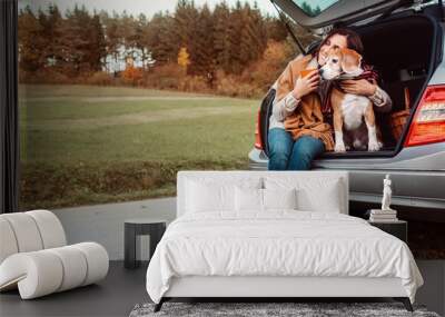 Woman with dog sit together in cat truck and warms цшер hot tea. Auto travel with pets concept image. Wall mural