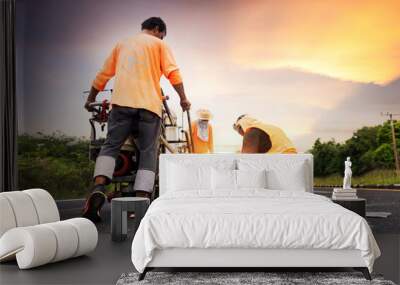 A road worker paints and observes pedestrian lines crossing the road on asphalt surface using a paint truck during a sidewalk maintenance work on the Asian Highway. Wall mural