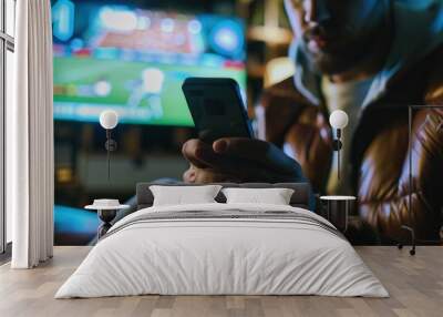 man holding a cell phone while betting online on a football match Wall mural