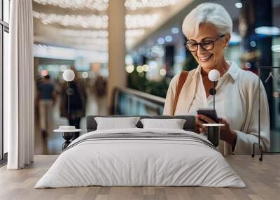 Relaxed elderly woman Middle-aged female customer holds smartphone using mobile app in shopping mall Wall mural