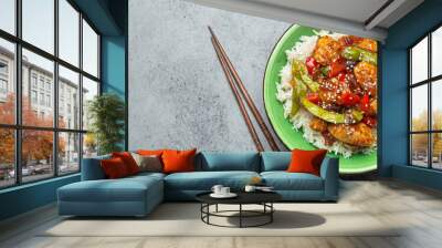 Asian sweet and sour sticky chicken with vegetables stir-fry and rice in ceramic bowl with chopsticks top view on gray rustic stone background, traditional Asian dish. Space for text Wall mural