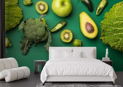 Creative layout healthy organic food concept made of green fruit and vegetables on green background flat lay: avocado, kale, broccoli, Brussels sprouts, kiwi, peppers, apple, cabbage top view
 Wall mural