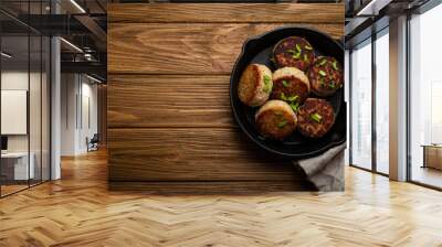 Homemade cutlets from fish, chicken or meat on black cast iron frying pan skillet on rustic wooden table, traditional meal roasted healthy cutlets in pan from above  Wall mural