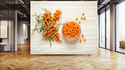 Sea buckthorn ripe berries in glass jar and branches with leaves top view on white wooden rustic background, great for skin, heart, vessels and immune system. Wall mural