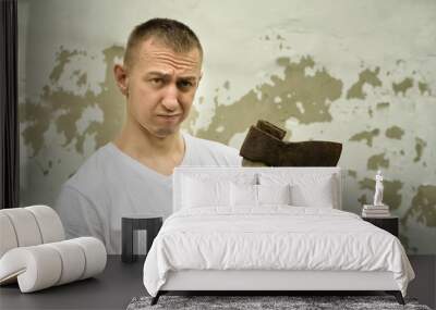 Angry man with an ax in his hand against the backdrop of a shabby wall Wall mural