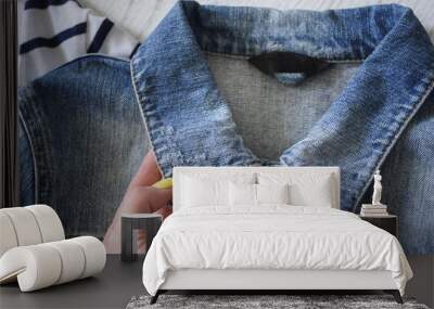 Collar of a denim jacket  in female hand. Fashionable concept Wall mural