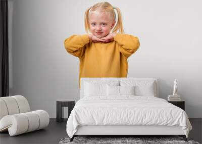 Portrait of a cute little girl with blond hair in a yellow sweater on a light background Wall mural