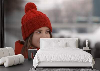 Portrait of a young girl in a red hat on a background of a winter street Wall mural