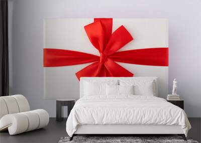 White box with red ribbon and bow on white background. Top view. Wall mural