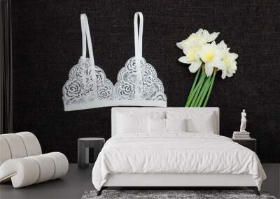 White lace bra and bouquet of daffodils on a black background. Fashionable concept Wall mural