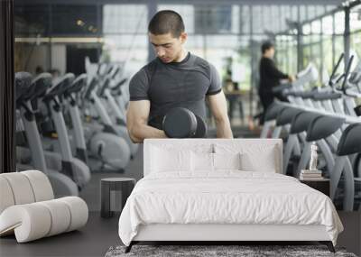 Asian men lifting dumbbells in the gym Wall mural