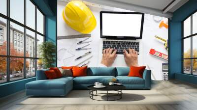 Top view, Architect or engineer hands working on blueprint plans with a laptop and pencil a ruler, calculator, and engineering tools. Architect or engineer working on blueprint in office. Wall mural