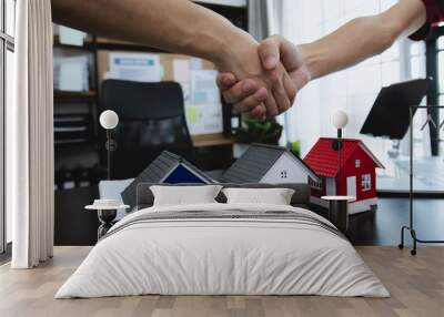 Business man and woman in formal attire shaking hands, and sell home model.   Wall mural