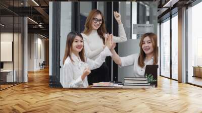 Group of young asian businesswoman working and brainstorming in workshop and analyzing marketing reports startup project infographics in the office. Wall mural