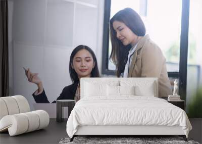 Two Asian young businesswomen working on computer with analyzing financial charts in the modern office, Business financial documents and planning idea project concept. Wall mural