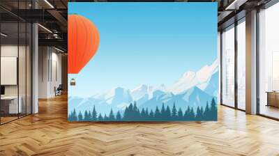 The vibrant orange hot air balloon soars above majestic snow-capped peaks, surrounded by lush green forest under a clear blue sky Wall mural