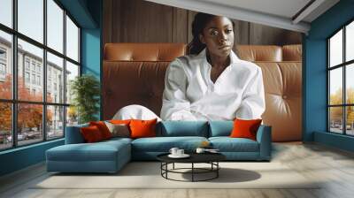 Thoughtful sensual afican american young woman in elegant suit is sitting on sofa in living room Wall mural