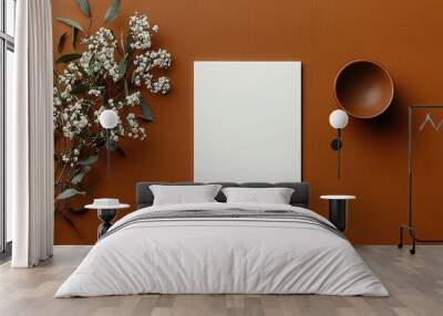 A minimalistic flat lay featuring a blank sheet, a small bowl, and white flowers on a warm brown surface. Wall mural