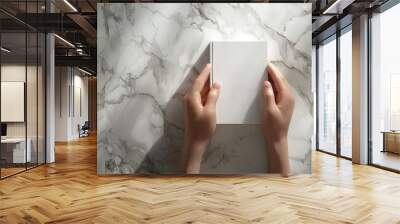 pair of hands gently holding a closed white book. The background is a high-resolution marble surface with subtle, intricate veins, rendered in ultra-detailed 8K with smooth textures. Wall mural