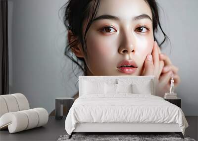 Studio portrait of a beautiful young Asian woman with cosmetics makeup or skin care on her face that makes her look pretty isolated on clean studio background. Wall mural