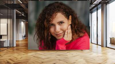 Close up portrait of a cheerful curly young woman smiling outdoors Wall mural